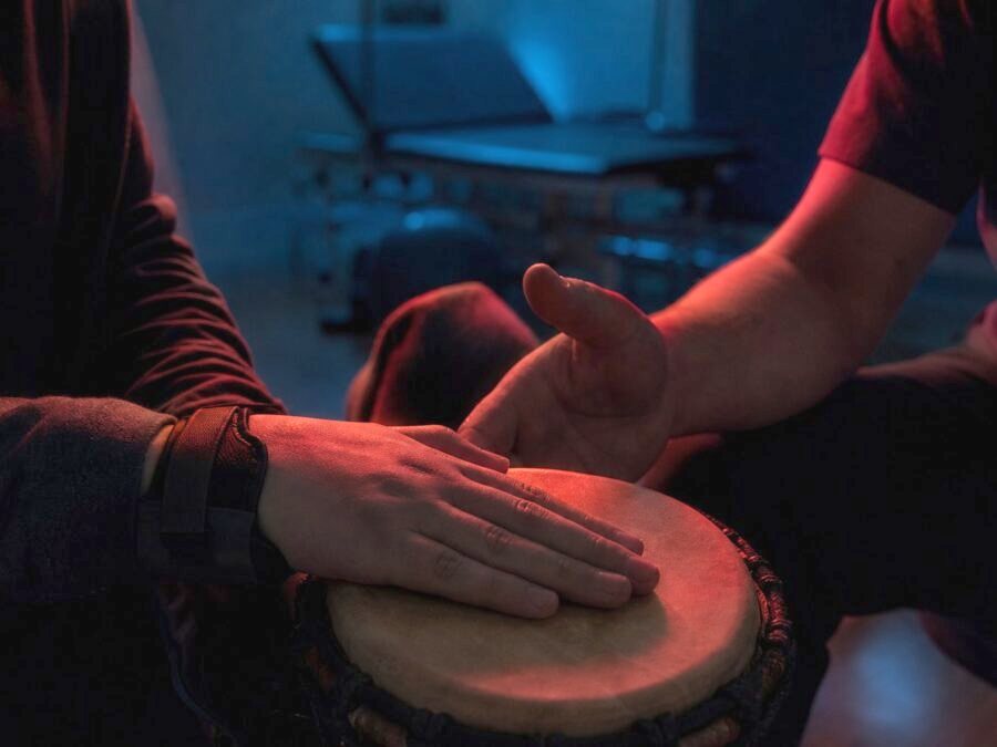 Hände in einem Reha-Raum trommeln gemeinsam auf einer kleinen Handtrommel
